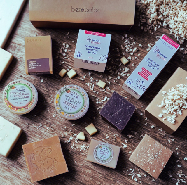 Přírodní bezobalové produkty pro péči o ekzematickou pokožku v zimě – tuhá mýdla, zinkové masti a regenerační balzámy značek Ponio, Medarek a Kvitok na dřevěném podkladu.